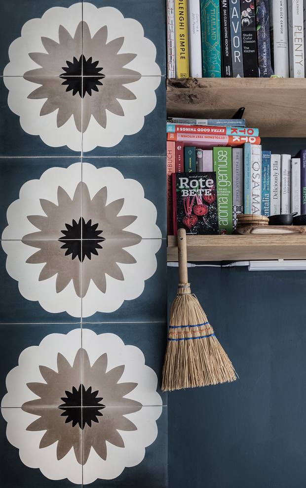 Wandgestaltung mit floraler Ornamentfliese und Bücherregal mit Kochbüchern 