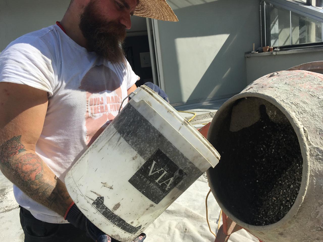 Arbeiter mit VIA Eimer vor Mischmaschine 