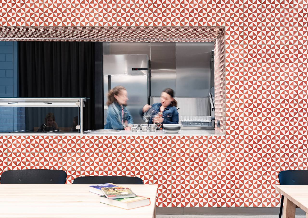 Schulkantine mit Thekenmöbel verkleidet mit Platten aus rot-weissen Dreiecken von VIA