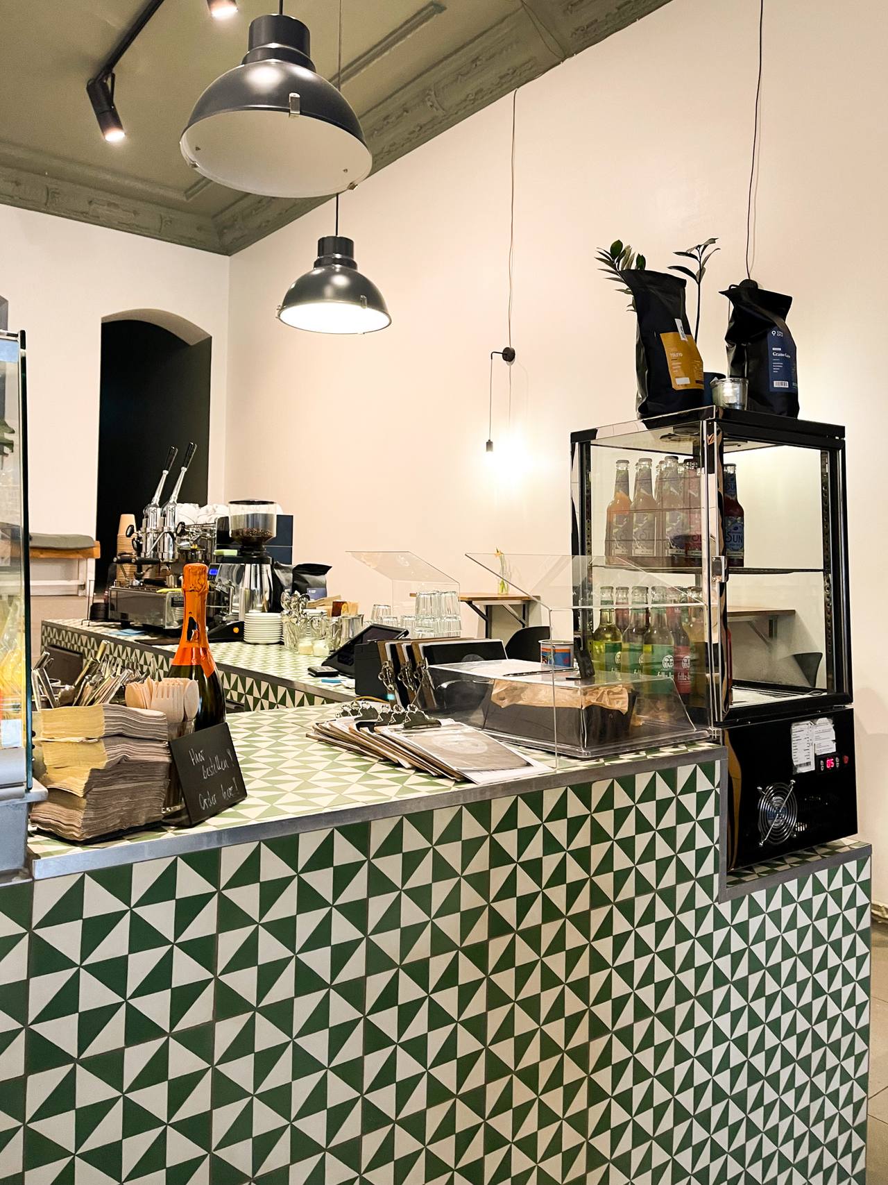 Bar-Theke mit VIA Zementmosaikplatten N° 10453 in grün-weißem Dreiecksmuster – handgefertigte Fliesen als grafisches Gestaltungselement im Innenraum. 