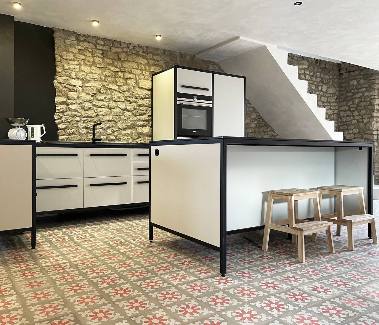 Gemusterter Zementmosaikboden in offener Wohnküche mit Sandsteinwand 