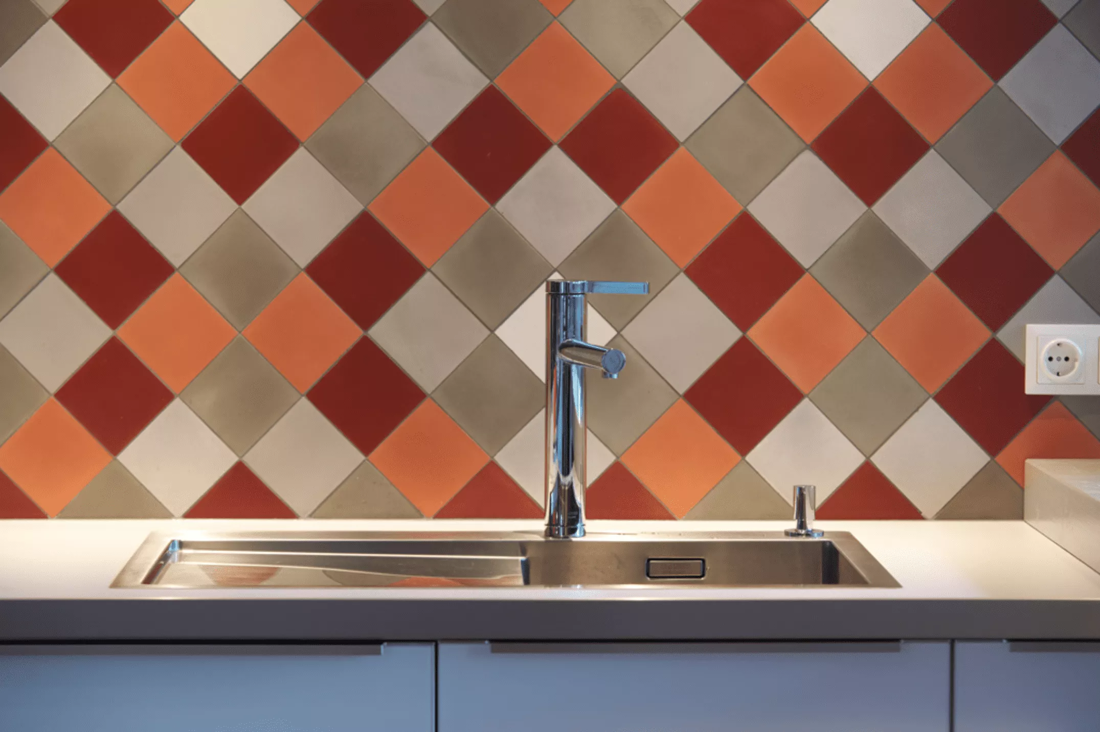 Spülbecken mit Terrazzofliesen in rot/grau/orange im Hintergrund