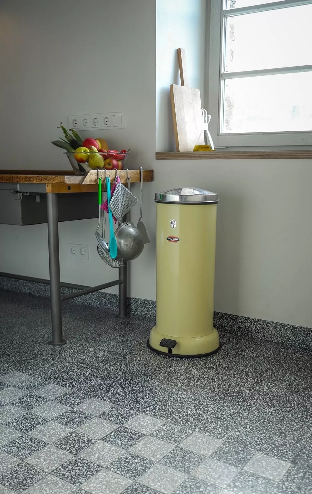 kariertes Muster an Terrazzofliesen in einem Zimmer mit Mülleimer und Tisch